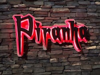 a neon sign that says piranha on a stone wall